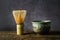 Japanese matcha green tea at homemade clay bowl with bamboo whisk on wooden table