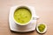 Japanese matcha green tea is poured into a white mug and on a white saucer in powder. Tea set on a textured napkin. Invigorating d