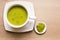 Japanese matcha green tea is poured into a white mug and on a white saucer in powder. Tea set on a textured napkin. Invigorating d