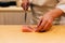 Japanese Omakase Chef cut Medium Fatty Bluefin Tuna Chutoro in Japanese neatly by knife on wooden kitchen counter.