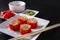 Japanese rolls with fish ROE on a white plate, ginger, wasabi, sticks on a black background, Japanese cuisine