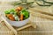 Japanese sharp snacks with peas and wasabi lie in a white glass bowl on a wooden stand on a bamboo lining