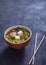 Japanese soup with tofu cheese and vegetables, chopsticks on black background. Copy spaes