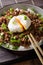 Japanese spicy beef Soboro with egg benedict, rice and green onion close-up. vertical