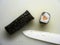 Japanese style rice nori roll with salmon near ceramic blade knife on cutting board top view