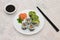 Japanese sushi plate. Salmon and shrimp rolls with avocado on white plate with decoration. Soy sauce and chopsticks. Top view.