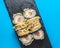Japanese Sushi Roll - Warm Sushi Roll with Salmon and Cream Cheese served on a black board over bright blue background
