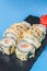 Japanese Sushi Roll - Warm Sushi Roll with Salmon and Cream Cheese served on a black board over bright blue background