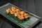 Japanese sushi volcano roll with black flying fish roe tobiko and Marinated salmon on top Served on bamboo leaves on black plate