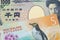 A Japanese thousand yen note paired with a orange, plastic five dollar bill from New Zealand.