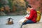 Japanese tourists sit and relax along the arashiyama river during the autumn leaves. With the shiba dog