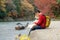 Japanese tourists sit and relax along the arashiyama river during the autumn leaves. With the shiba dog