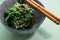 Japanese Wakame seaweed salad with sesame seeds with chopsticks in bowl