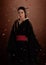 Japanese woman samurai wearing kimono on brown background and flower petals. Japanese culture