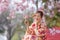 Japanese woman in traditional kimono dress holding sweet hanami dango dessert while walking in the park at cherry blossom tree