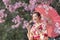 Japanese woman in traditional kimono dress holding umbrella and sweet hanami dango dessert while walking in the park at cherry