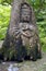 Japanese wood carving of a goddess with coins in a green forest