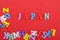 JAPANESE word on red background composed from colorful abc alphabet block wooden letters, copy space for ad text