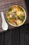 Japanese Zosui rice soup with egg, mushrooms, vegetables and chicken meat close-up in a bowl. vertical top view