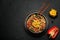 Japchae in black bowl on dark slate table top. Korean cuisine glass chapchae noodles dish with vegetables and meat