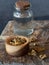 Jar of alcohol, wooden bowl of propolis granules on piece of wood.