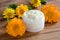 A jar of calendula cream, with calendula flowers in the background