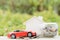 Jar of coins and red car on pile of coin on blurred green natural background. Saving money and investment concept