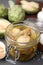 Jar of delicious artichokes pickled in olive oil on grey table, closeup