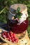 Jar of delicious lingonberry jam and red berries on wicker basket outdoors