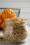 Jar of dried orange zest seasoning and fresh fruits on light grey table