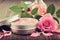 Jar with a homemade moisturizing beauty cream and pink rose flower. Making of cosmetic products.