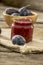 Jar of homemade plum jam with wooden bowl of juicy ripe fresh pl