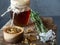 Jar of honey, flowers and wooden bowl of propolis granules on piece of wood.