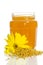 The jar of honey near a pile of pollen and flower