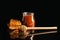 Jar of honey, wooden dipper and honeycomb against dark background