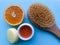 A jar of orange scrub, a body brush and half an orange on a blue background. Spa concept, body cleansing and moisturizing, anti-