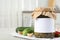 Jar of pickled cucumbers with  sticker on grey table in kitchen, space for text