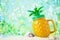 Jar of pineapple juice on the sand with shells on the summer sea background