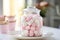 A jar of pink and white marshmallows basks in diffused light on a windowsill