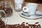 Jar with spilled coffee beans on linen tablecloth with cup of espresso full with spoon.