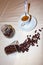 Jar with spilled coffee beans on linen tablecloth with cup of espresso full with spoon