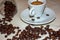 Jar with spilled coffee beans on linen tablecloth with cup of espresso full with spoon