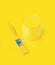 A jar of spilling yellow paint and a brush on a yellow background. Trending colors