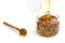 A jar of walnuts is filled with honey, a spoon with dripping honey on the table