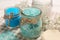 Jars with different sea salt and flowers on towel, closeup