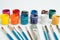 Jars of gouache paint in different colors. Next to it are brushes of various sizes. Artist`s kit. Side view. White background.