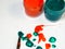 Jars of green and red acrylic paint on a white background and splattered paint on the table