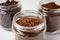 Jars with instant, ground coffee and roasted beans on white table, closeup