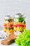 Jars with layering vegan salad for healthy lunch with place for text