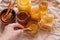 Jars of natural honey bees of different kind, honeycomb and pollen in bowl on table. Human hand, close-up